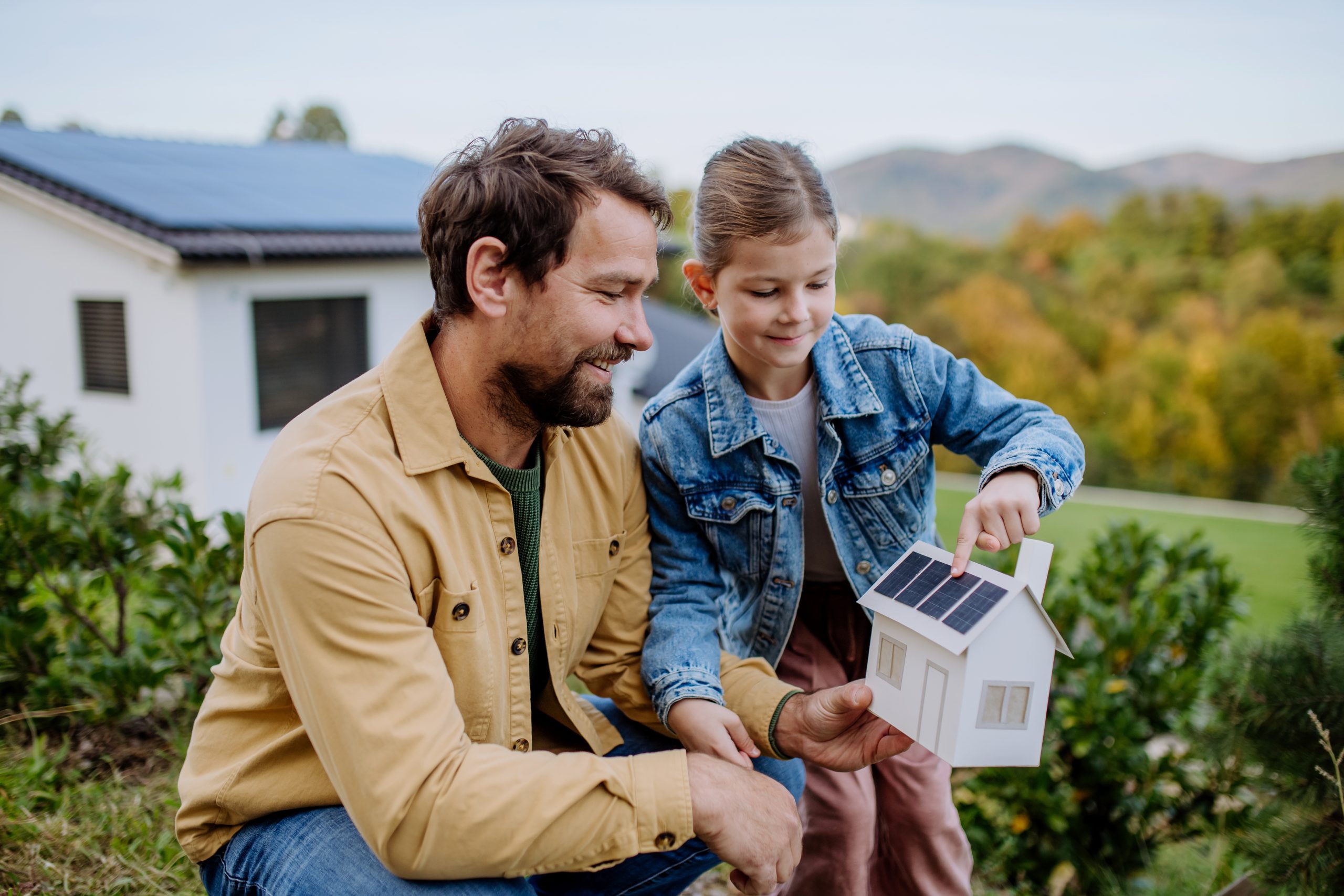 daughter showing father a 3D model of a home with solar panels on the roof